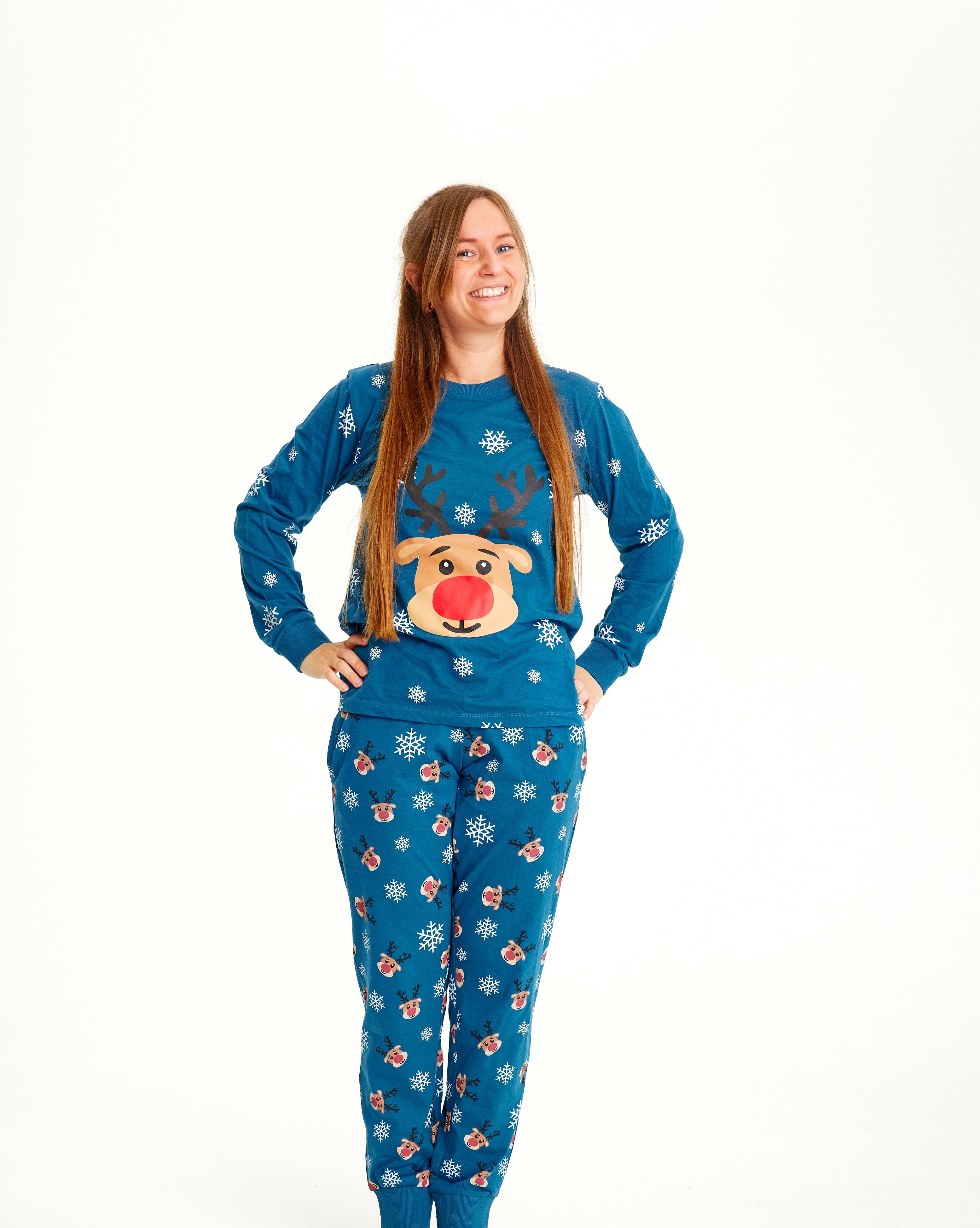 Een vrouw met haar handen langs haar zij in een blauwe kerstpyjama met Rudolph erop.